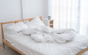 White Messy Bed In A White Room In Morning Without People
